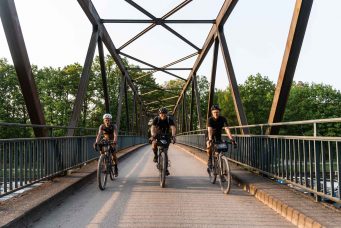 3 gravelbiker fahren über eine ruhrbrücke