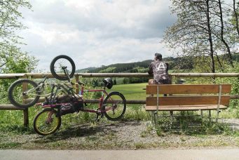 Christian sitzt auf einer bank an einem schönen aussichtspunkt, das rad nebenan abgestellt. Ein tolles bike bikepacking abenteuer!